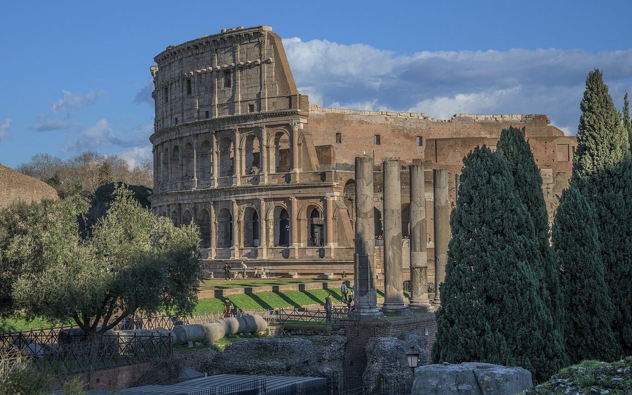 The many arched levels of a huge ancient stone amphitheater under a blue sky