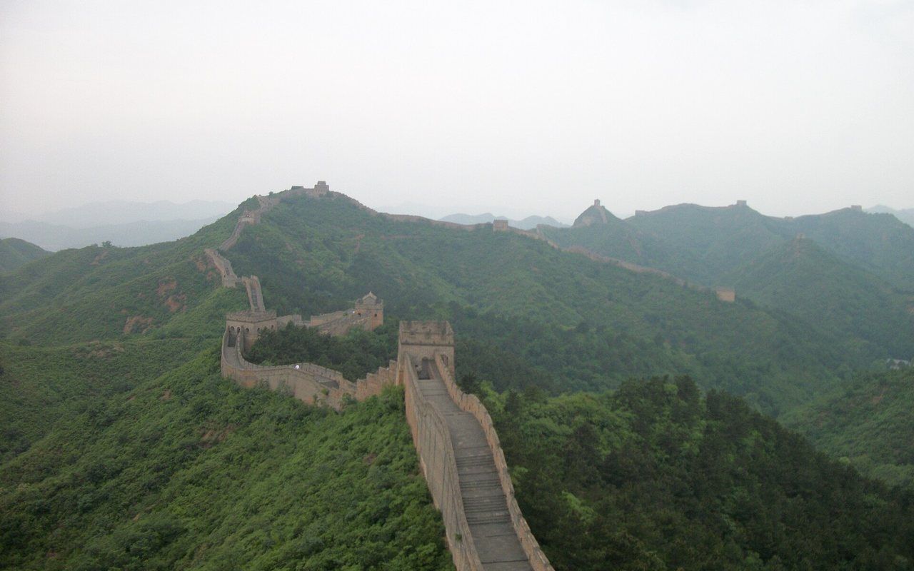 Stone watchtowers and a long wall following steep green mountain ridges