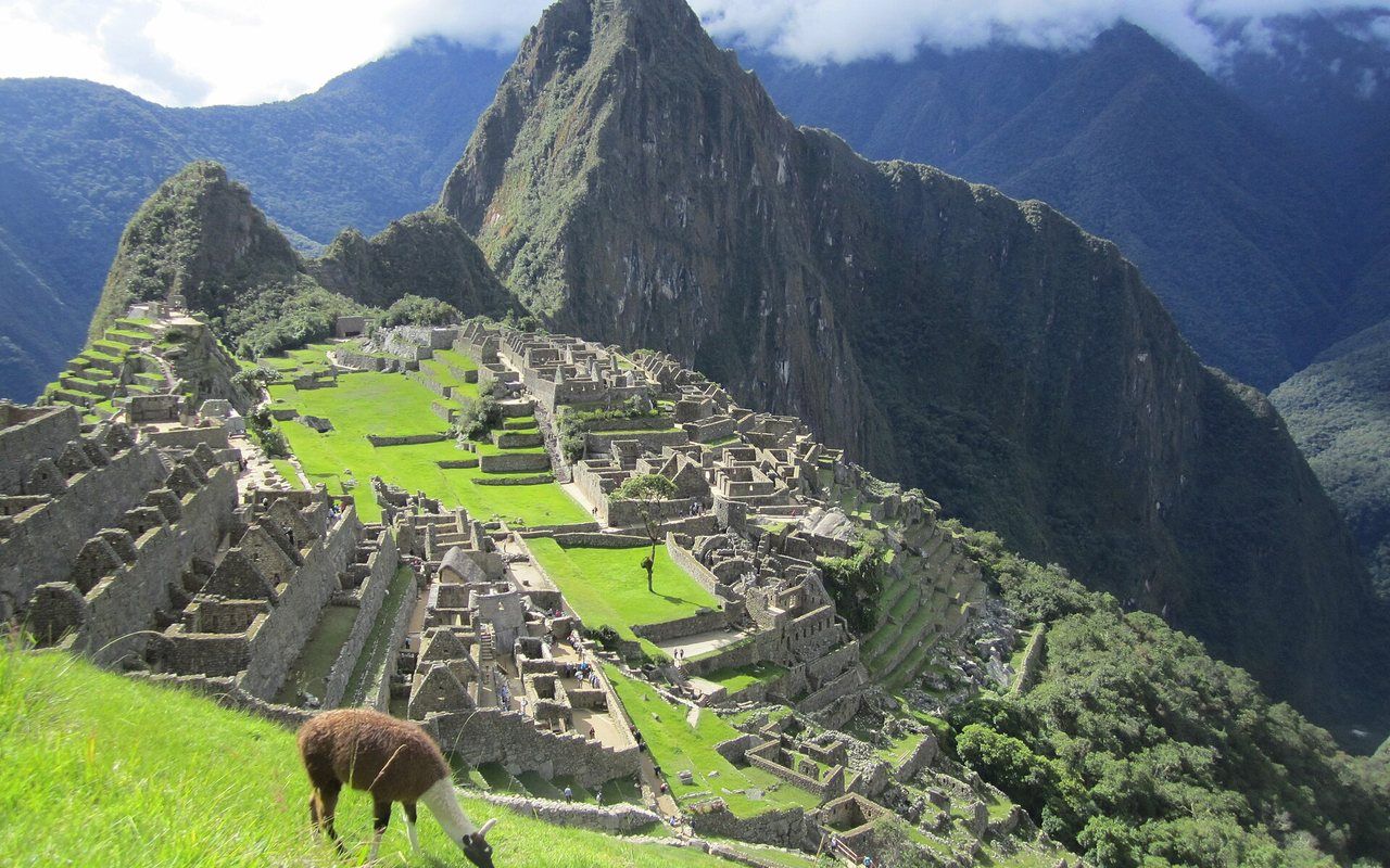 Stone terraces and roofless ruins among steep green tropical peaks