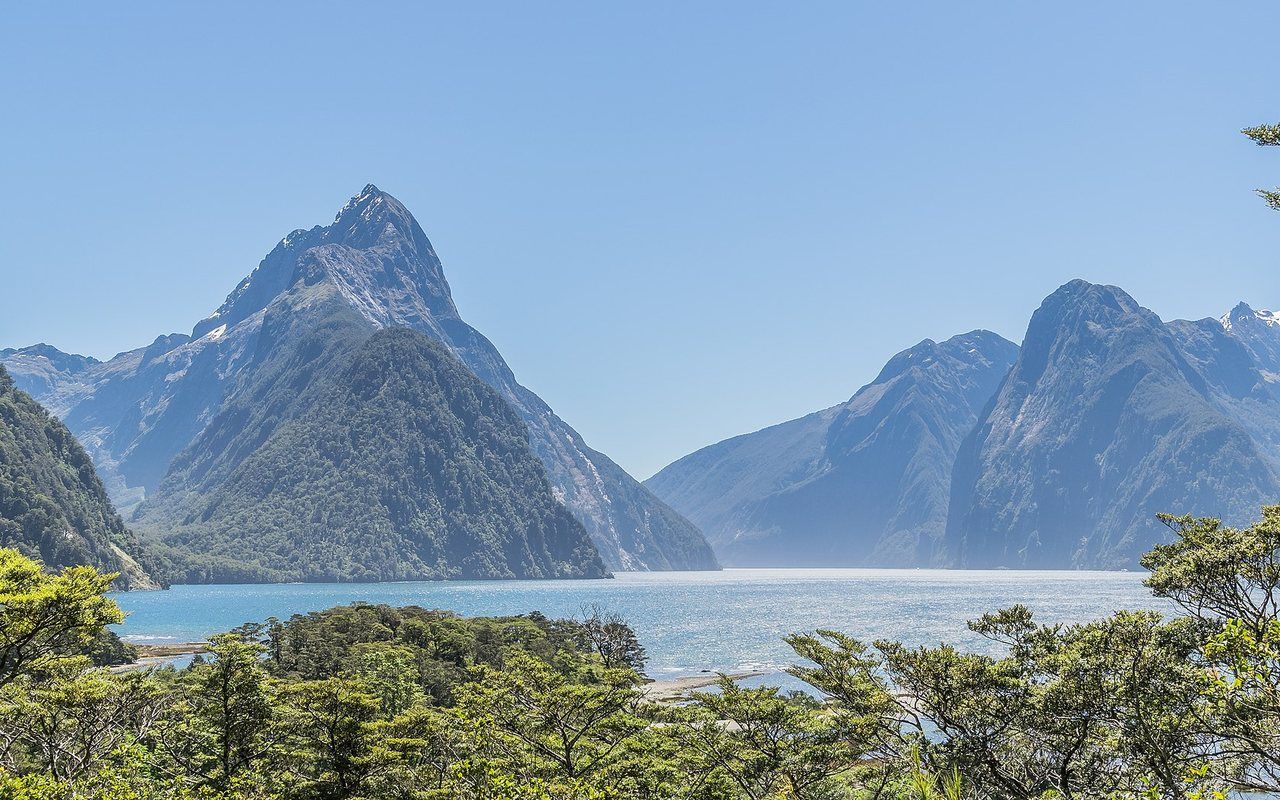 Steep forested cliffs and waterfalls surrounding a calm narrow sea inlet