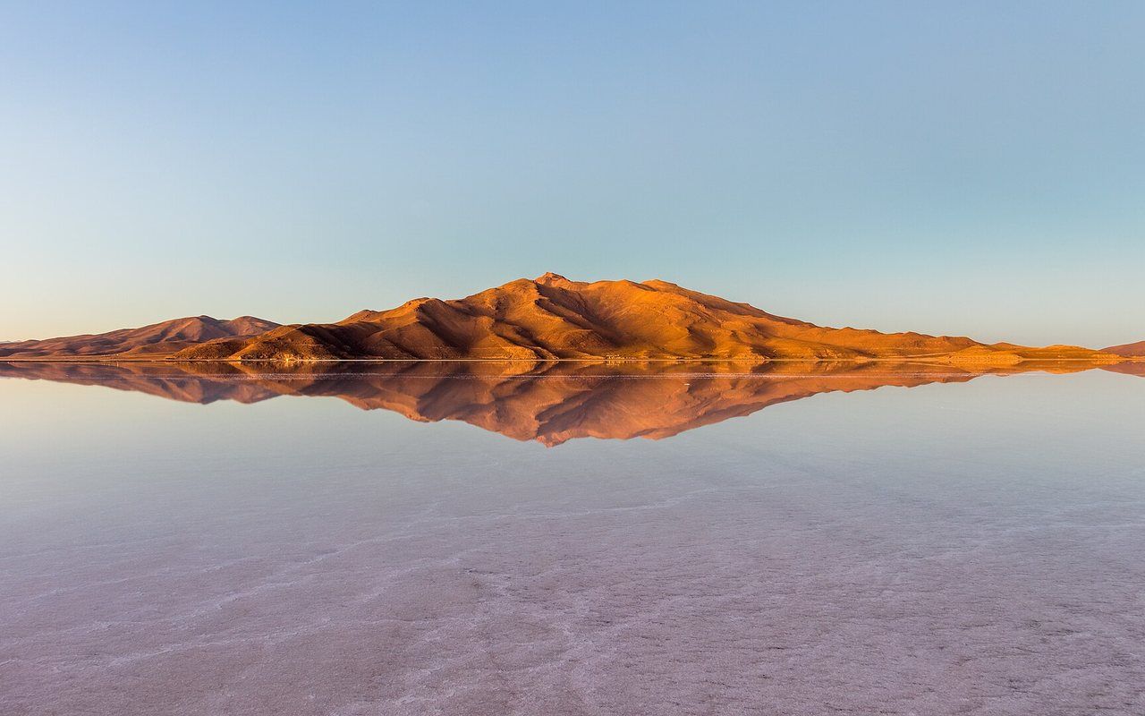 A vast bright white salt flat stretching beneath a deep blue sky