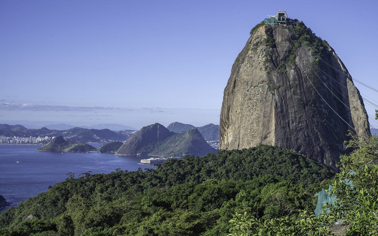 A steep rounded granite peak rising beside a broad bay and coastal city